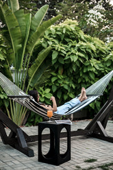 Standalone Wooden Hammock - Sculptural black wooden frame with a striped woven textile in a lush garden setting by Ali Khan Studio Karachi Pakistan