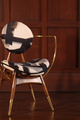 HALO Dining Chair - Sculptural brass and wood chair with patterned upholstery in a luxury wood-paneled room by Ali Khan Studio