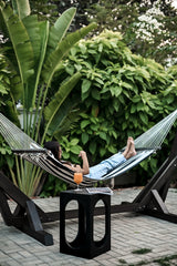 Standalone Wooden Hammock - Sculptural black wooden frame with a striped woven textile in a lush garden setting by Ali Khan Studio Karachi Pakistan