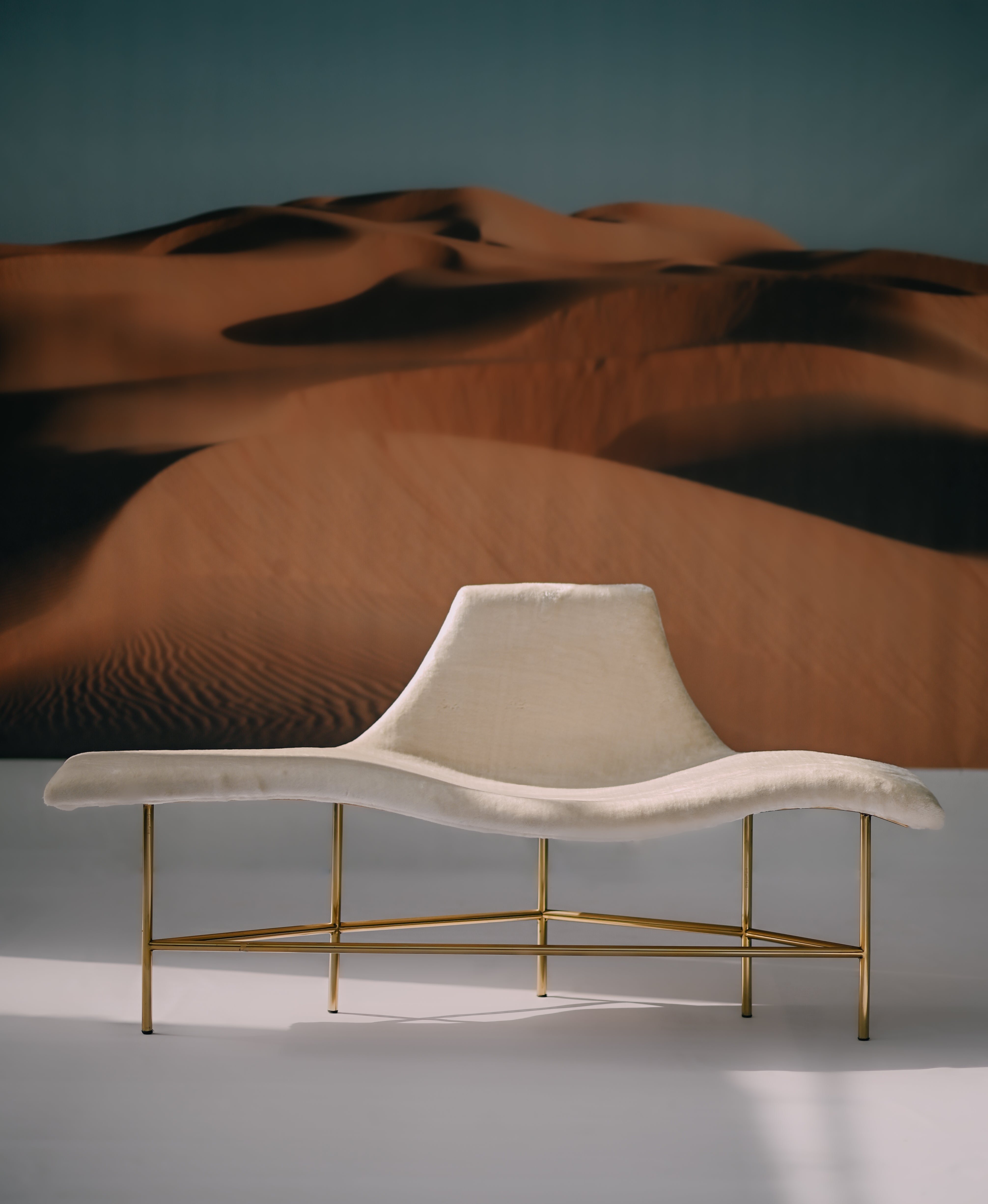 Verona Chaise - Sculptural white upholstered lounge seat on a golden tripod frame by Ali Khan Studio Karachi Pakistan